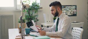 man sitting at desk deciding between to papers